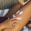 Close-up of a hand applying sunscreen on a leg with a smiley. Sunny and fun outdoor setting.