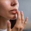 Close-up of a woman's hand applying lip balm, highlighting beauty care routine.